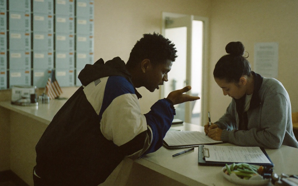 A walk-in client explaining while the receptionist writes on a paper form